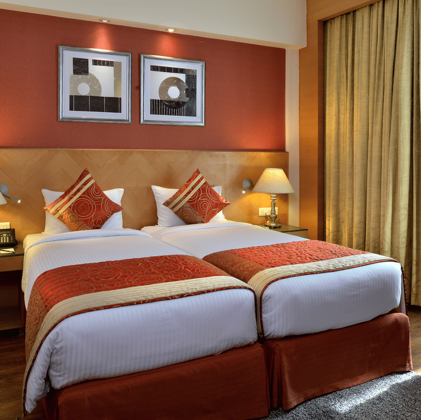 Stylish room at Savoy Suites, Manesar with warm orange accent wall, modern furnishings, and comfortable seating area