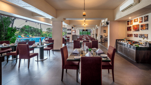 Outdoor dining area at Golden Tulip, offering a cosy atmosphere with wooden furniture and greenery.