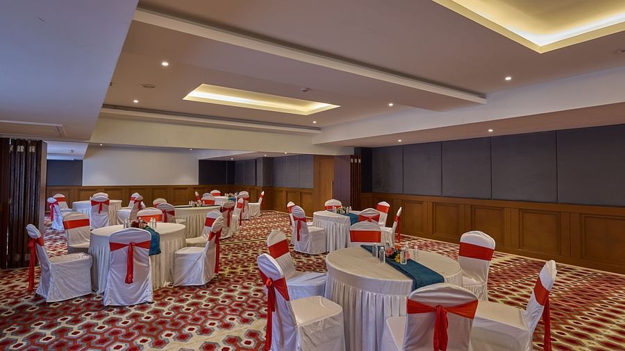 chairs with white cloths and red ribbons set up in a cluster arrangement in Mandapa ballroom at Grand Continent, Mahabalipuram