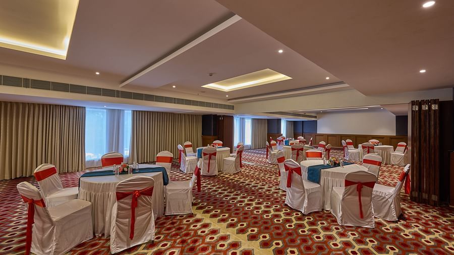 red ribbons around white cloth-covered chairs set up in cluster arrangement in our ballroom in mahabalipuram - Grand Continent, Mahabalipuram