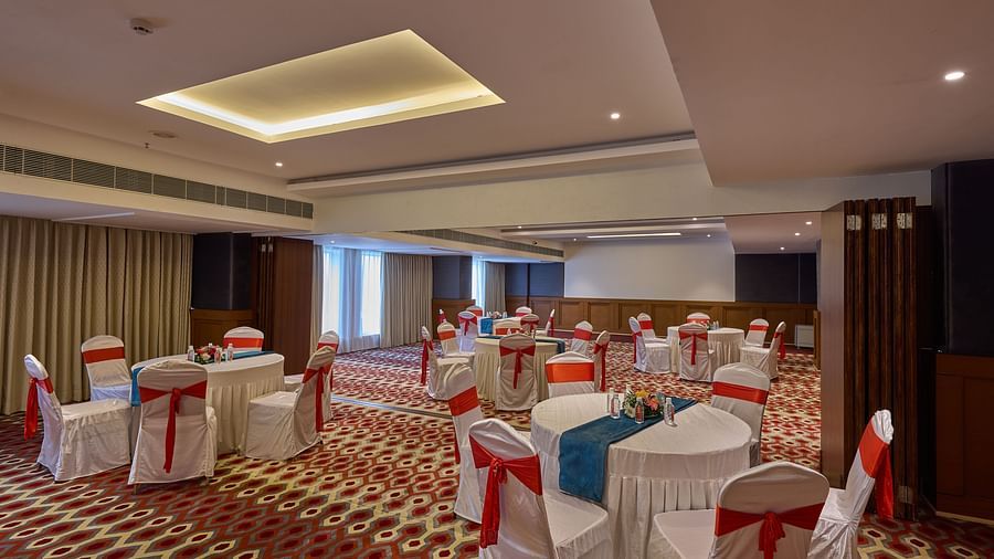 chairs with white cloths and red ribbons set up in a cluster arrangement in the banquet hall at Grand Continent, Mahabalipuram