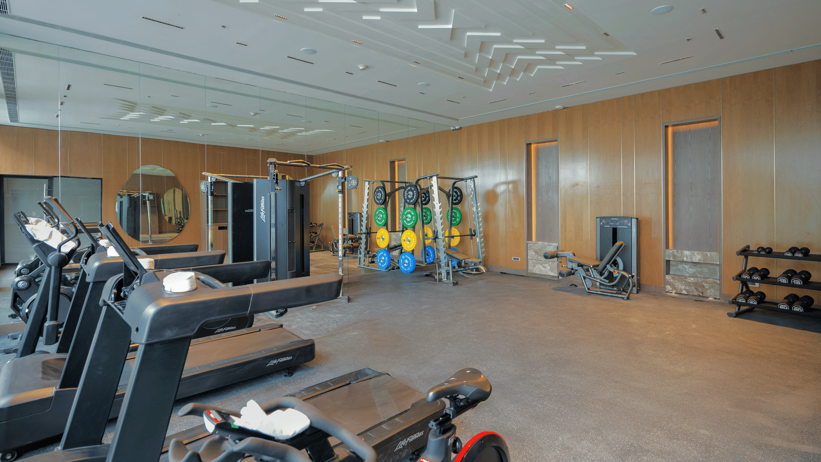 Fully equipped gym with treadmills, weights, and vibrant wall at Merlis Hotel, Coimbatore.