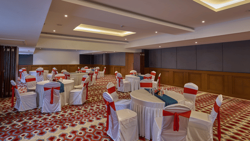 chairs with white cloths and red ribbons set up in a cluster arrangement in Mandapa ballroom at Grand Continent, Mahabalipuram