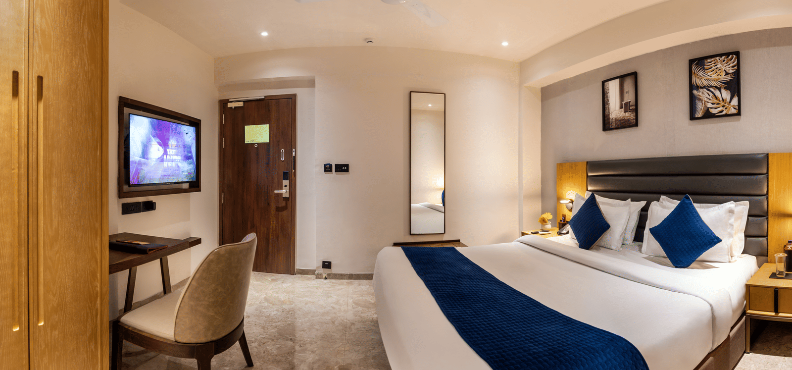 Spacious hotel room with plush bed, wardrobe, and seating area at Lords Studio Inn, Jamnagar.