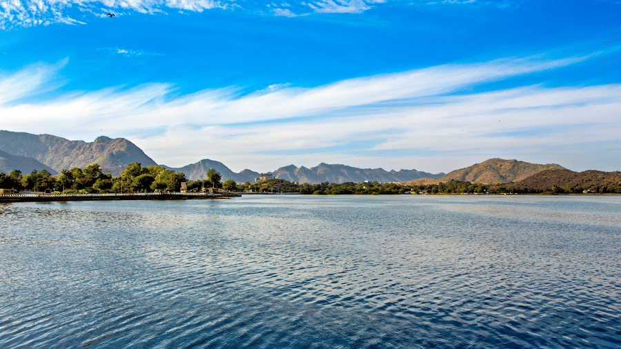 The Fateh Sagar Lake with its surrounding mountains under a bright blue sky.