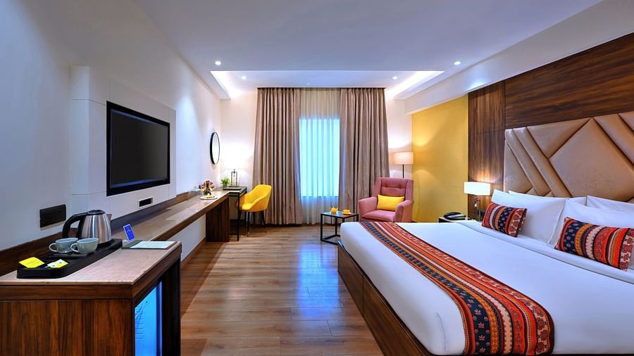 An image of a large bed placed in front of a wall-mounted television in our Executive Room in Agra - Golden Tulip, Agra