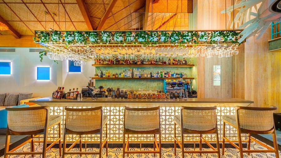 Cozy bar setup with wicker chairs, hanging lights, and a decorative fish sculpture in a bright, welcoming ambiance.
