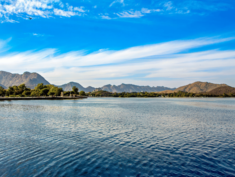 Clear blue Fateh Sagar Lake with rippling water distant mountains and bright sky reflecting serene calmness across Udaipur surroundings