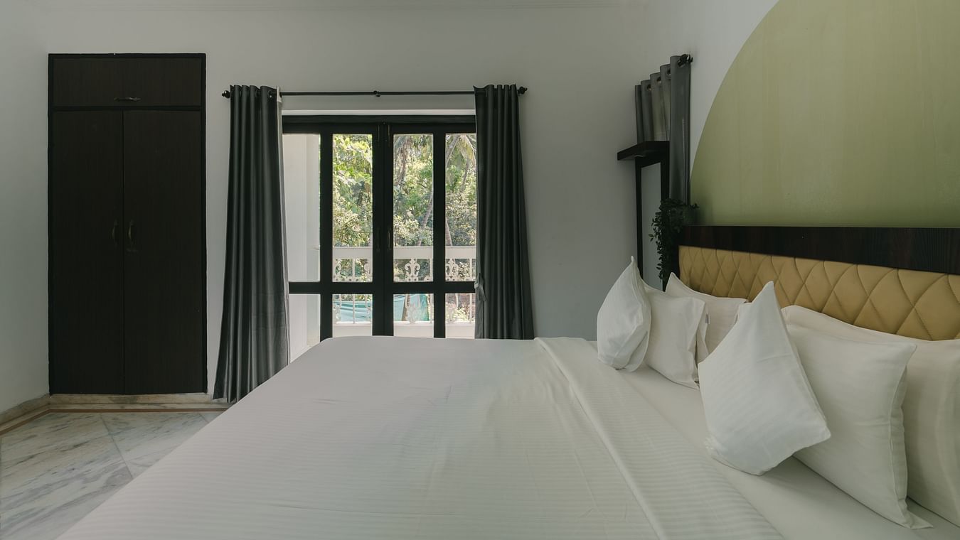 Well-lit bedroom with luxurious bedding and serene decor in the Three BHK Deluxe Villa at Richmonde Ananta Elite, Goa.