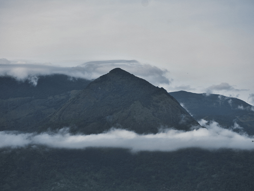 A wide shot of a hill covered with white clouds.