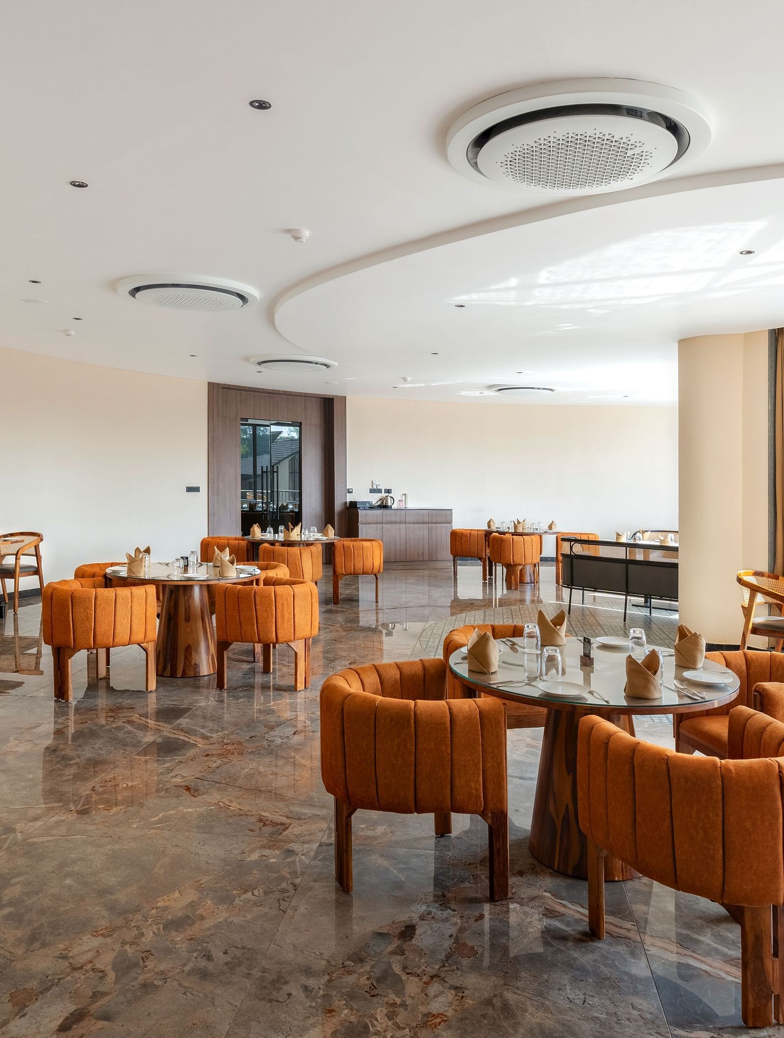 Fine Dine with tables, chairs, and large windows at The Qualia Resort Club & Brewery, Udaipur.