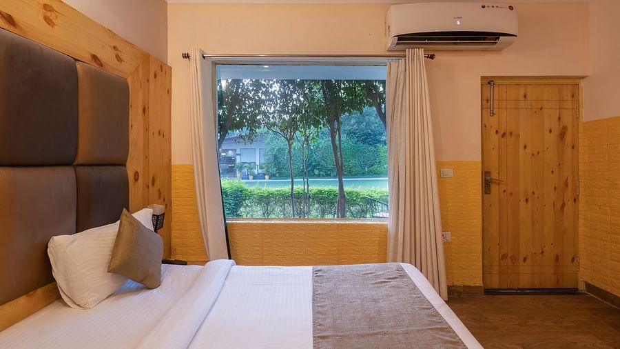 Room with large window and lawn view at The Tattwaa Corbett Spa & Resort.