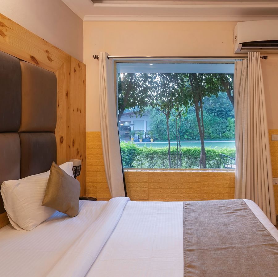 Room with large window and lawn view at The Tattwaa Corbett Spa & Resort.