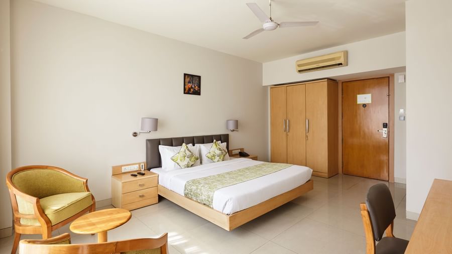 Hotels Mahape, Navi Mumbai, featuring a large bed and a small seating area.