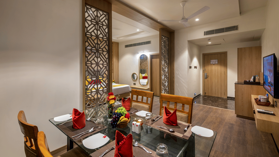 Sitting area of a suite at Lords Inn Somnath, featuring an entertainment unit and a neatly set up in-room dining area.