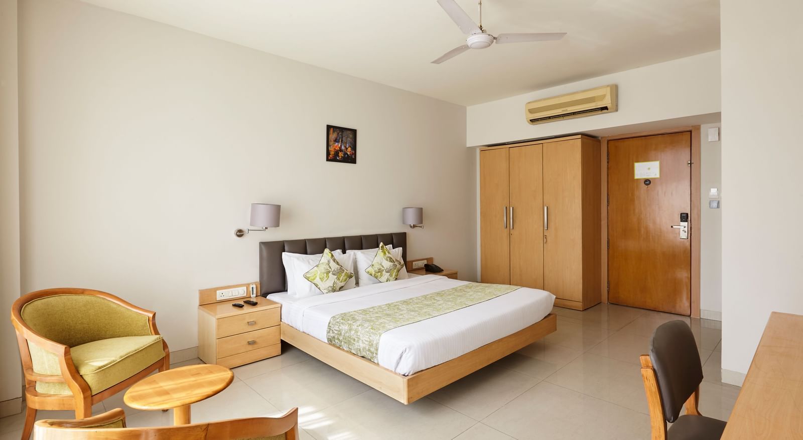 Hotels Mahape, Navi Mumbai, featuring a large bed and a small seating area.