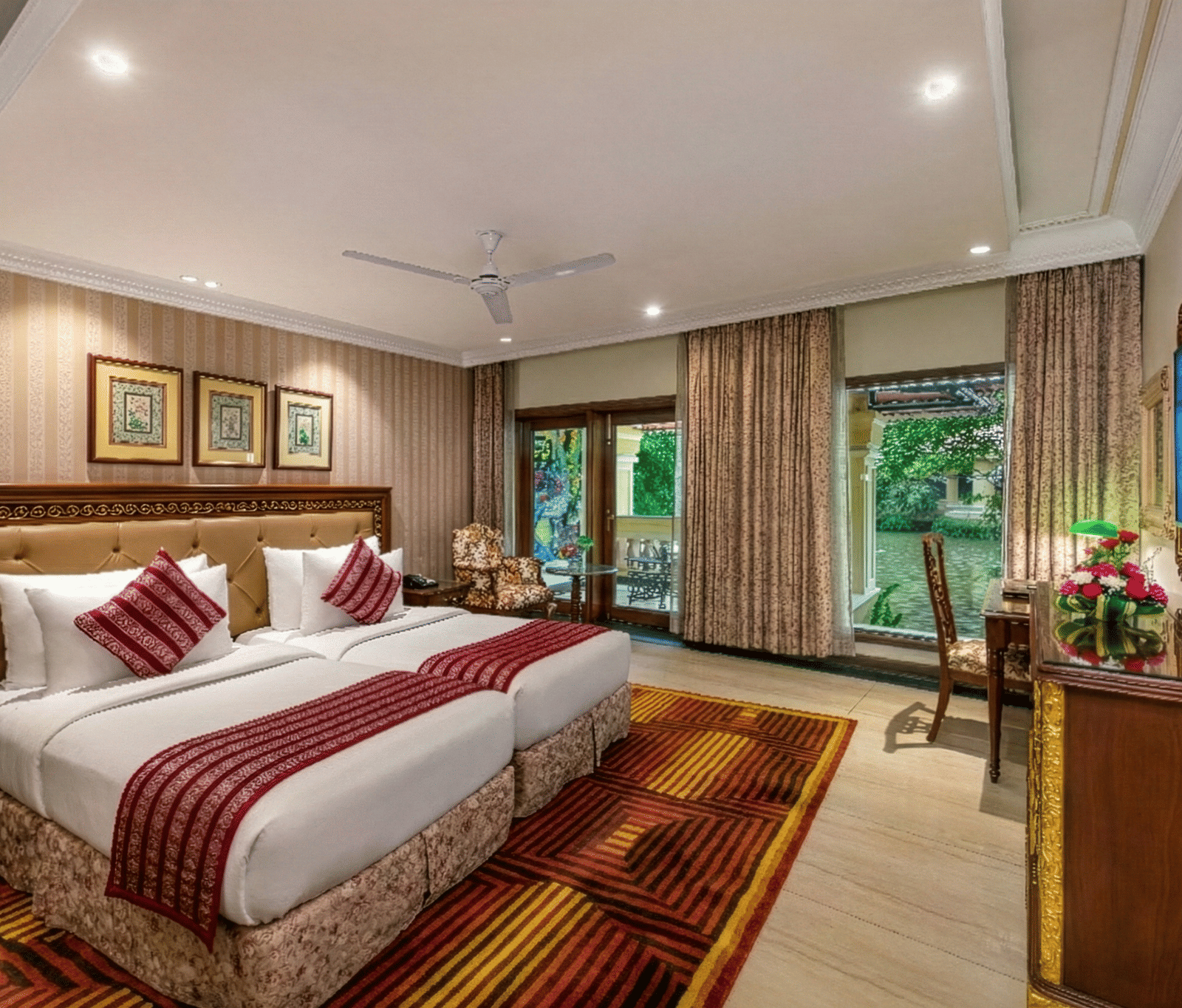 Twin bed Executive Cottage at Mayfair Lagoon Bhubaneswar with two neatly made beds, vibrant red and gold furnishings, and garden-facing windows