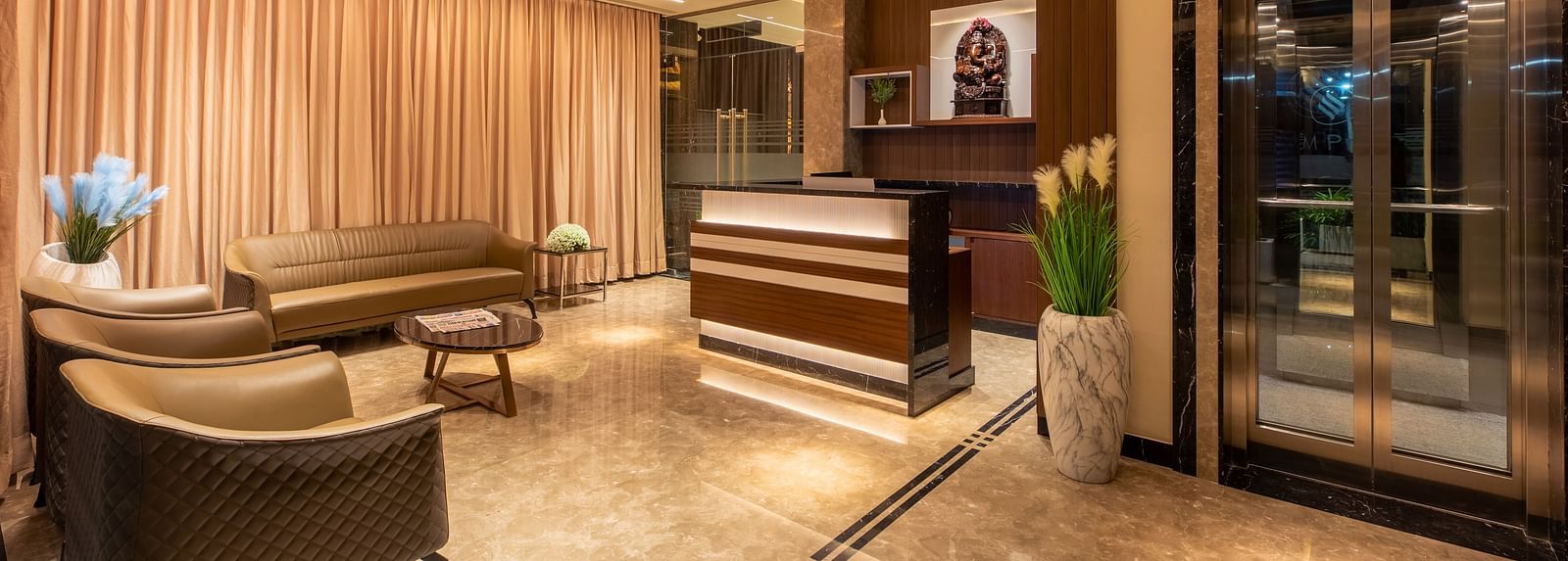 An image showcasing the reception area, featuring sofas and a table at M Pro Palace.