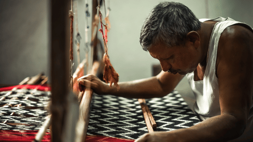 a person working on a handloom making intricate designs