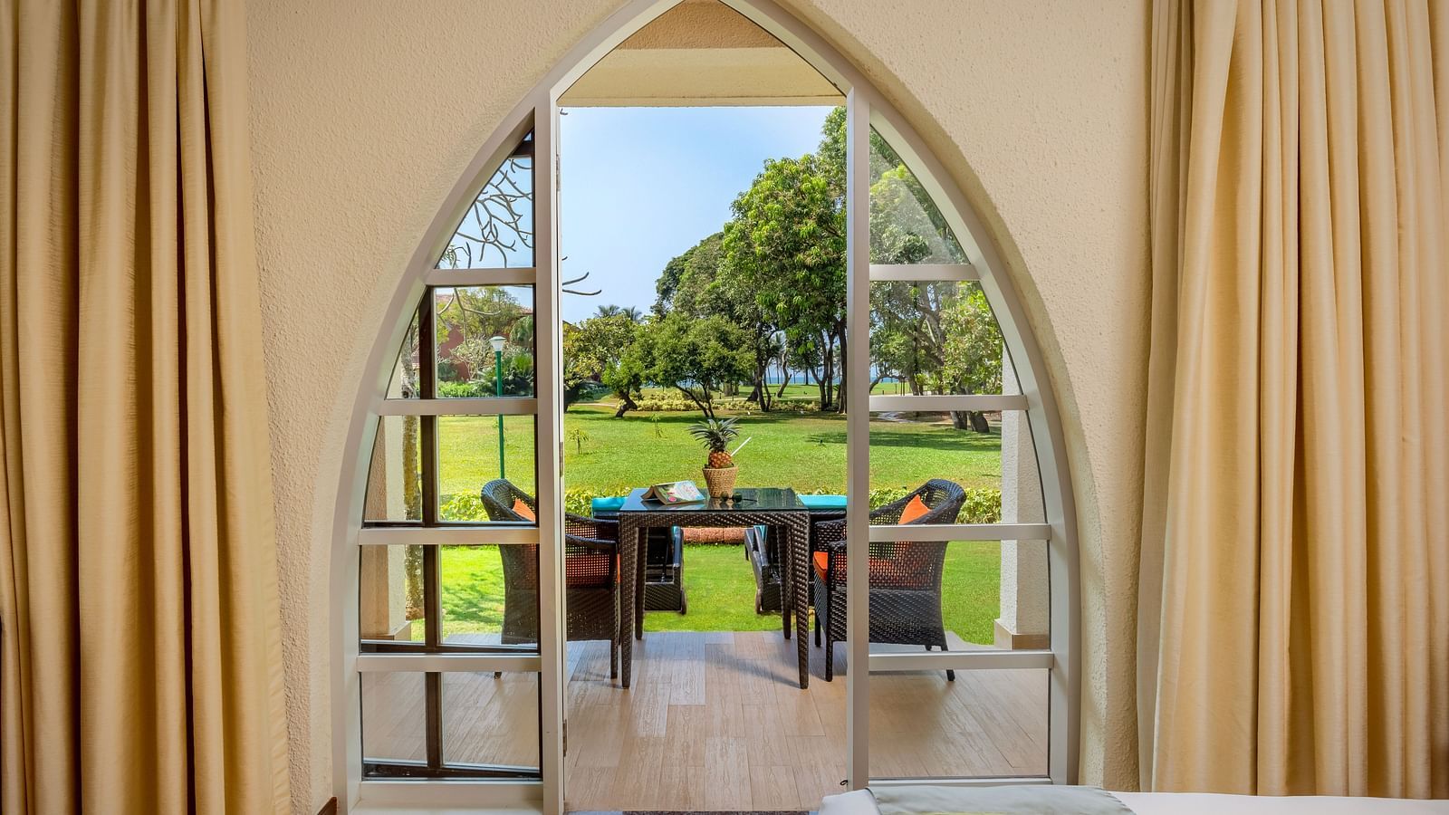 the balcony door with two chairs and a table inside Garden Villa - Caravela Beach Resort Goa