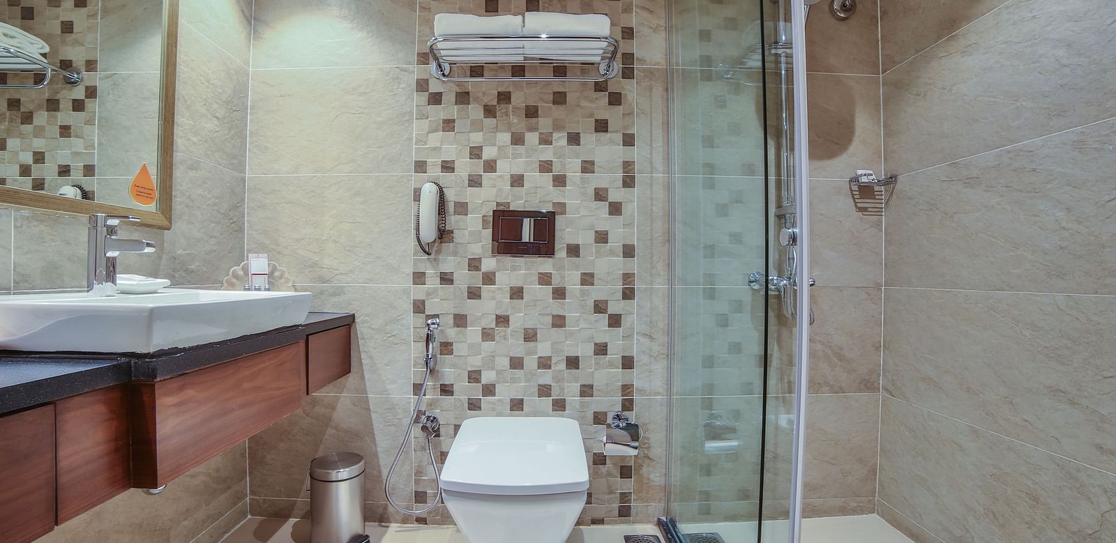 A modern hotel bathroom with patterned tiles, wood accents, and a glass shower enclosure A grand hotel suite with an opulent red and white decor, large bed, and seating area, reflecting a traditional style at Sitara Luxury Hotel in Hyderabad near Ramoji Fi