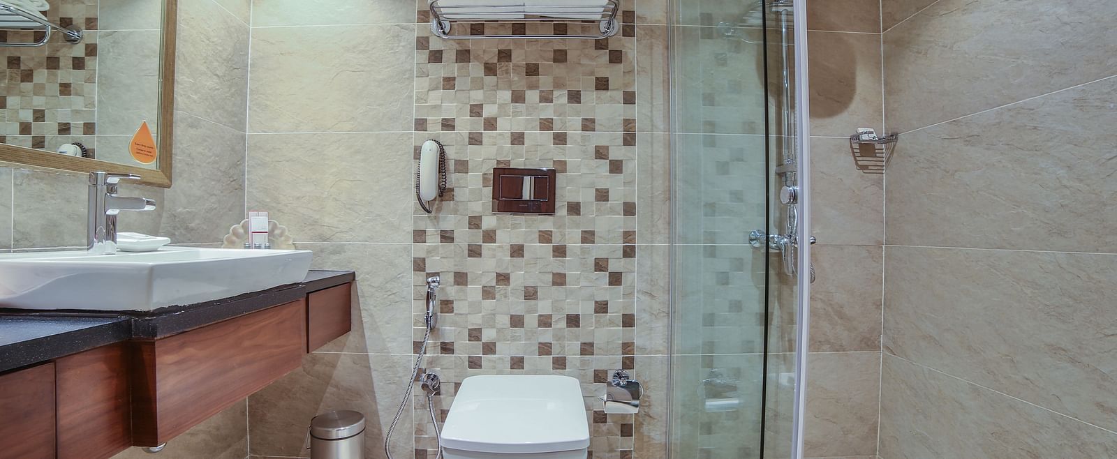 A modern hotel bathroom with patterned tiles, wood accents, and a glass shower enclosure A grand hotel suite with an opulent red and white decor, large bed, and seating area, reflecting a traditional style at Sitara Luxury Hotel in Hyderabad near Ramoji Fi