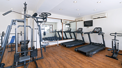 A clean and well-equipped hotel gym with various exercise machines, including treadmills and a weight machine - Clarks Avadh, Lucknow