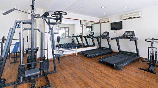 A clean and well-equipped hotel gym with various exercise machines, including treadmills and a weight machine - Clarks Avadh, Lucknow