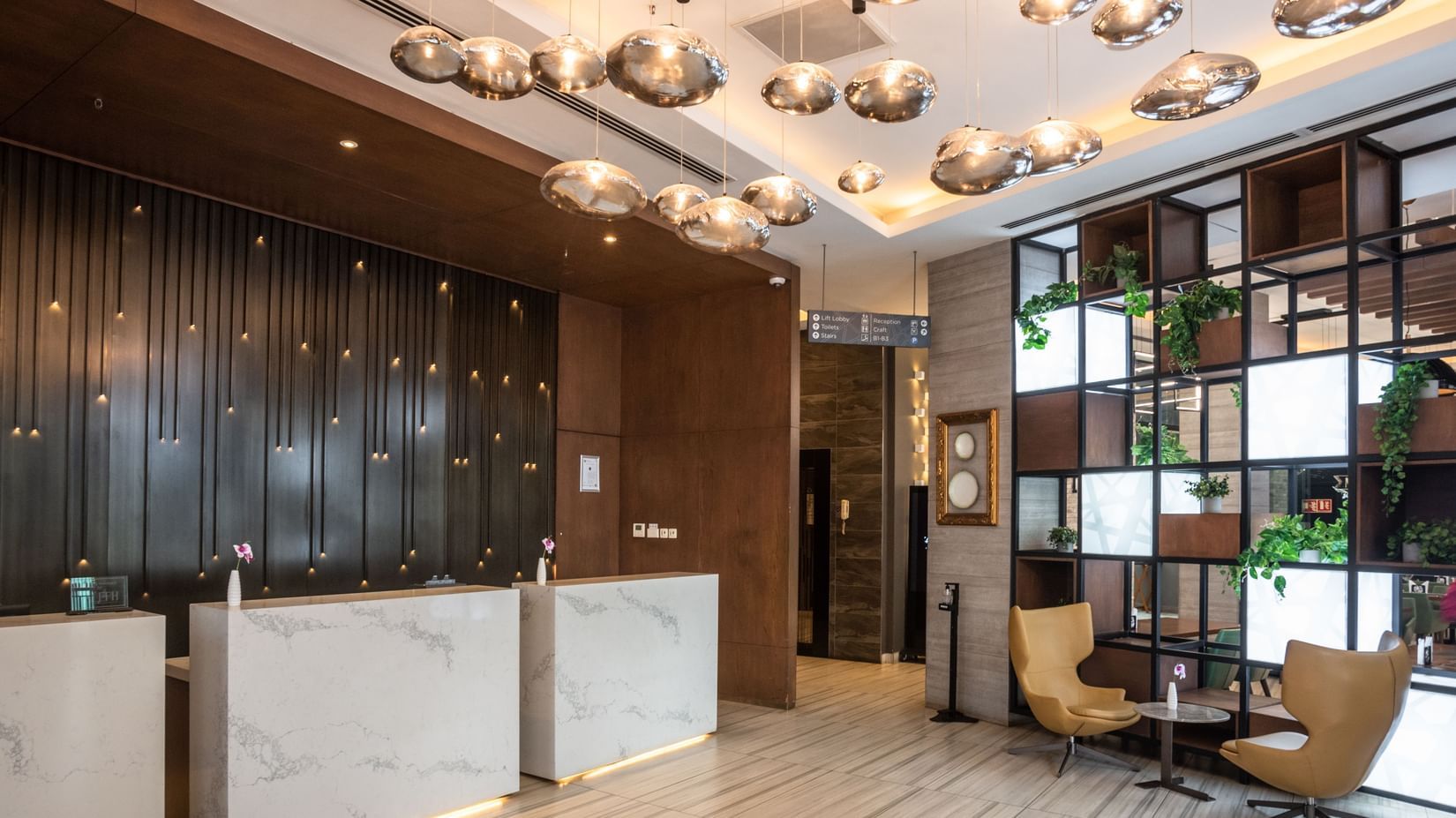 Lobby at Best Western Premier Westlands featuring a marble-fronted reception desk, plush chairs, and artistic lighting fixtures
