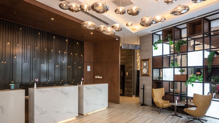Lobby at Best Western Premier Westlands featuring a marble-fronted reception desk, plush chairs, and artistic lighting fixtures