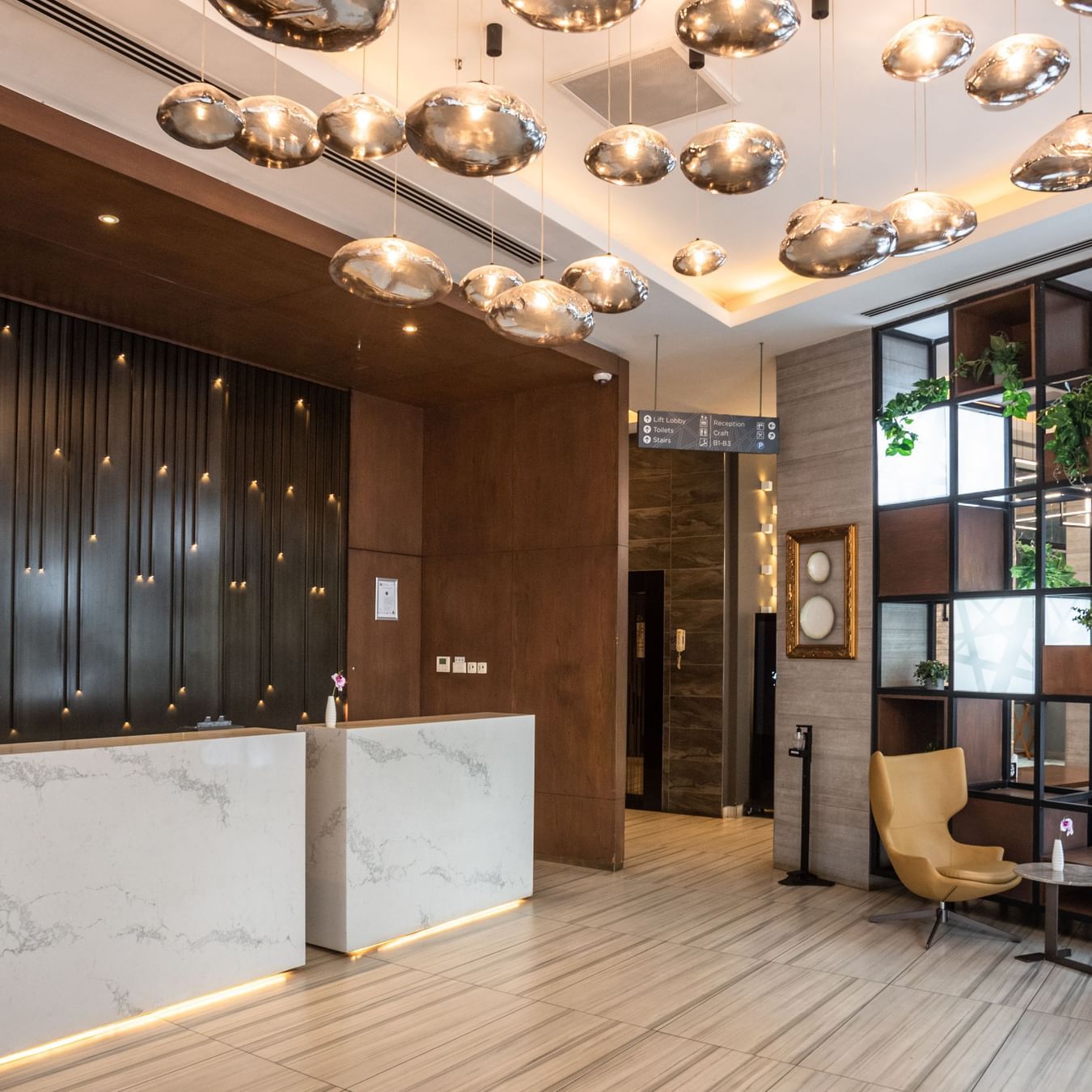 Lobby at Best Western Premier Westlands featuring a marble-fronted reception desk, plush chairs, and artistic lighting fixtures