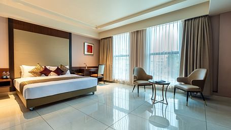 An image of a room with a bed, complemented by large windows on the side at M Pro Palace.