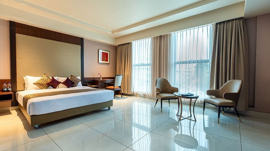 An image of a room with a bed, complemented by large windows on the side at M Pro Palace.