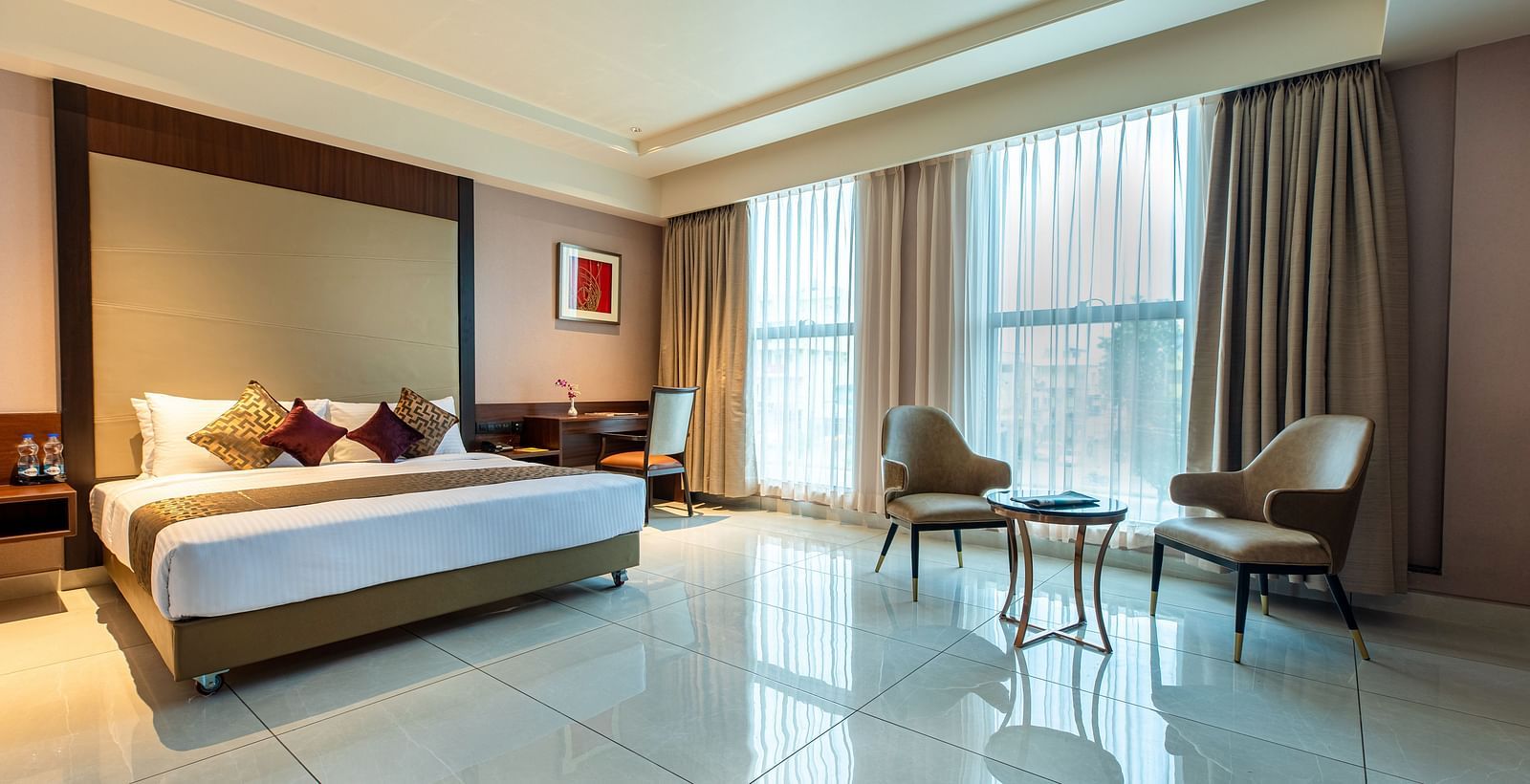 An image of a room with a bed, complemented by large windows on the side at M Pro Palace.