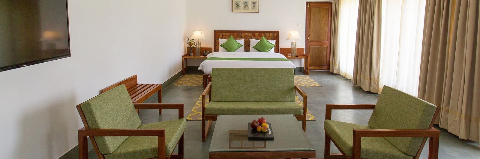 A room at Saraca Resort & Spa Corbett with a double bed and a seating arrangement around a coffee table