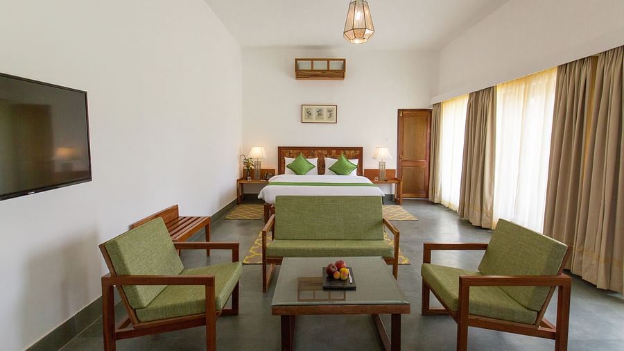 A room at Saraca Resort & Spa Corbett with a double bed and a seating arrangement around a coffee table
