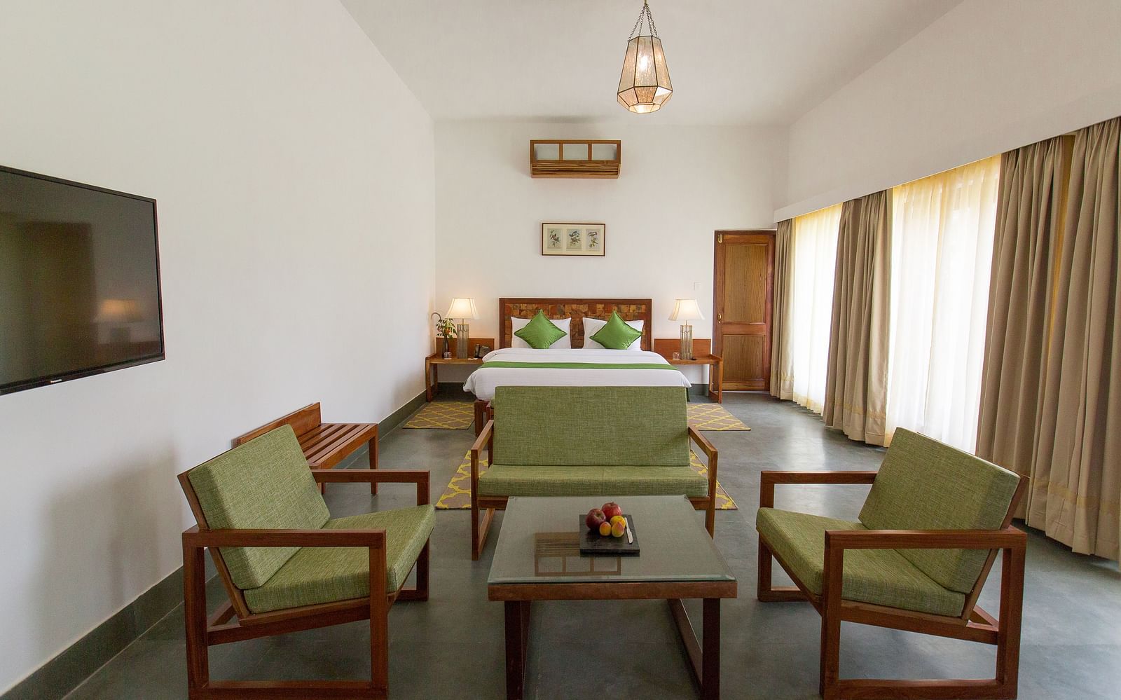 A room at Saraca Resort & Spa Corbett with a double bed and a seating arrangement around a coffee table