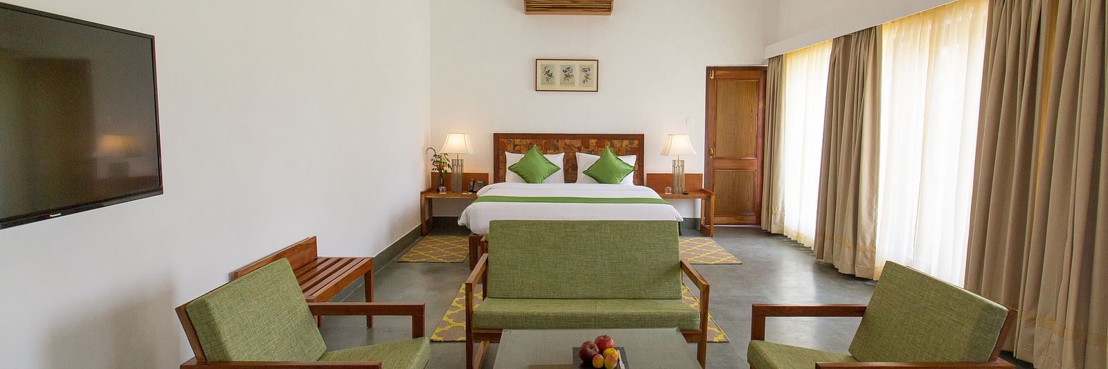 A room at Saraca Resort & Spa Corbett with a double bed and a seating arrangement around a coffee table
