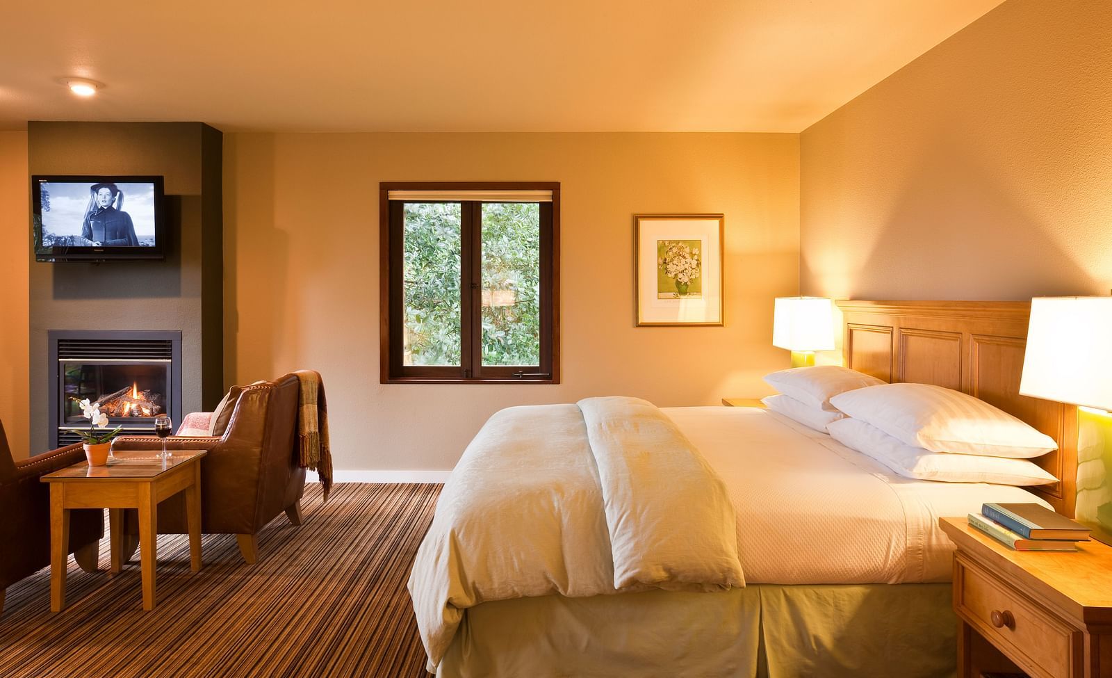 A spacious, sun-lit room with a king bed, a seating area, and warm decor - Brewery Gulch Inn & Spa