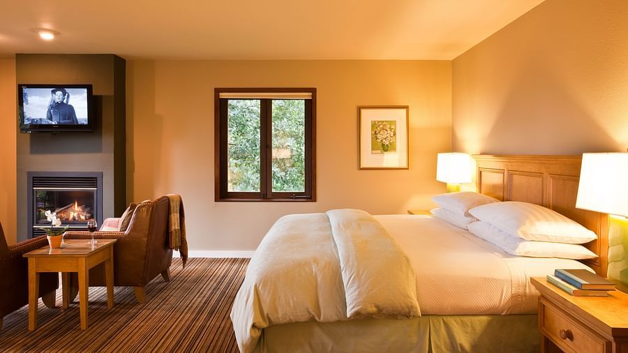 A spacious, sun-lit room with a king bed, a seating area, and warm decor - Brewery Gulch Inn & Spa