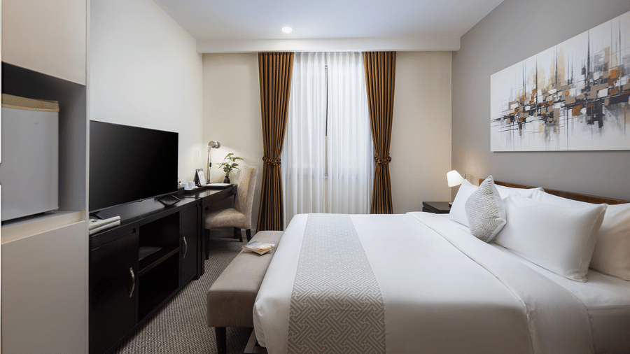 Studio with Workspace at Central Mansions, Phnom Penh showcasing a queen bed, workspace, television, and large windows.
