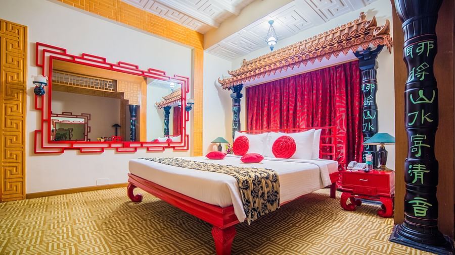 A vibrant hotel bedroom with a red and white color scheme, traditional decor, and a comfortable bed at Sitara Luxury Hotel in Hyderabad near Ramoji Film City.