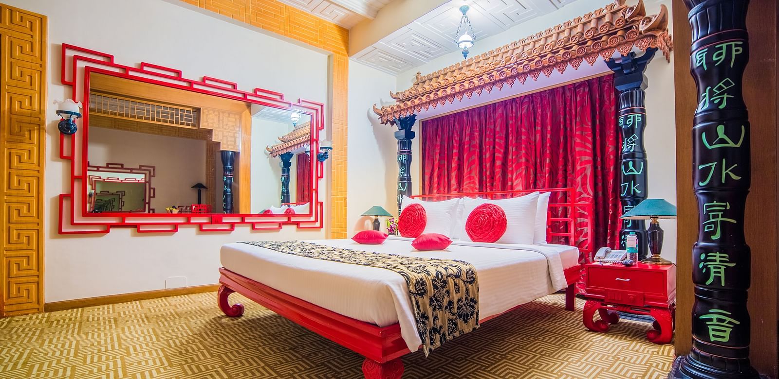 A vibrant hotel bedroom with a red and white color scheme, traditional decor, and a comfortable bed at Sitara Luxury Hotel in Hyderabad near Ramoji Film City.