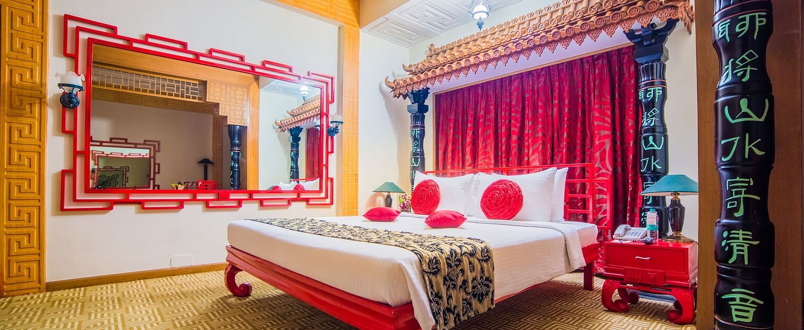 A vibrant hotel bedroom with a red and white color scheme, traditional decor, and a comfortable bed at Sitara Luxury Hotel in Hyderabad near Ramoji Film City.