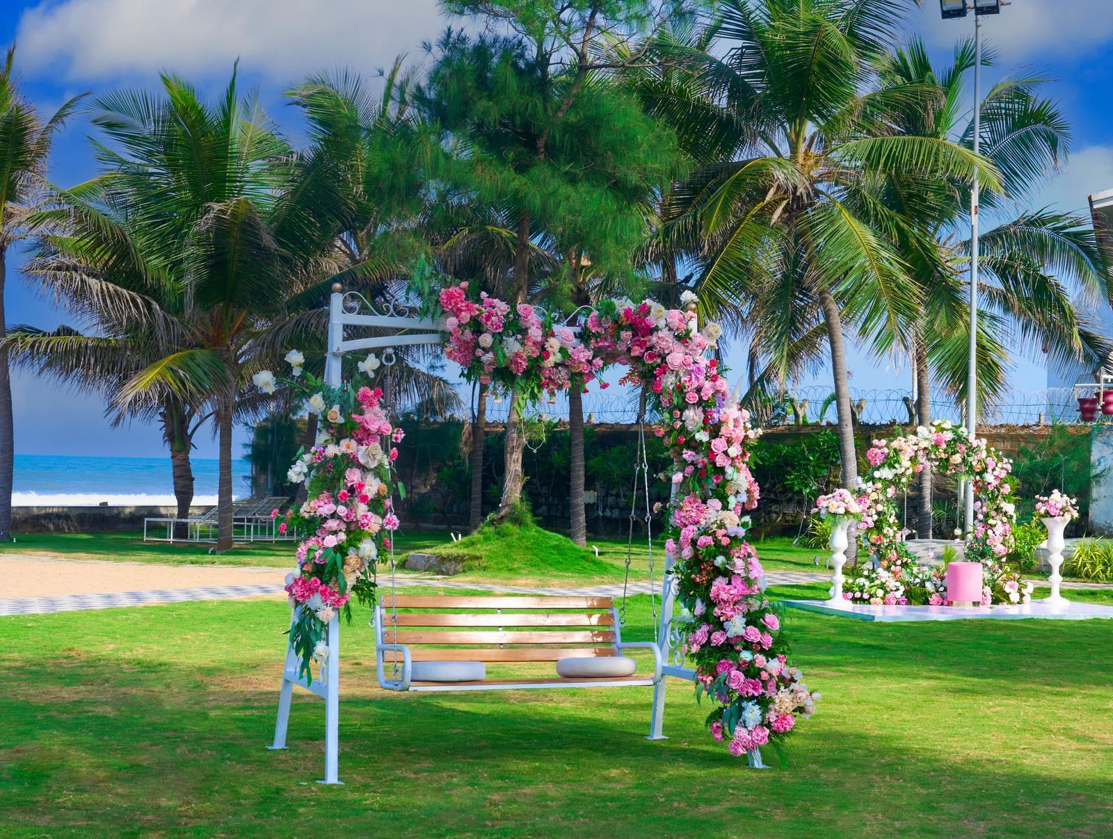 A flowery decorated swing in a scenic outdoor lawn with trees at the background at Grande Bay Resort & Spa.