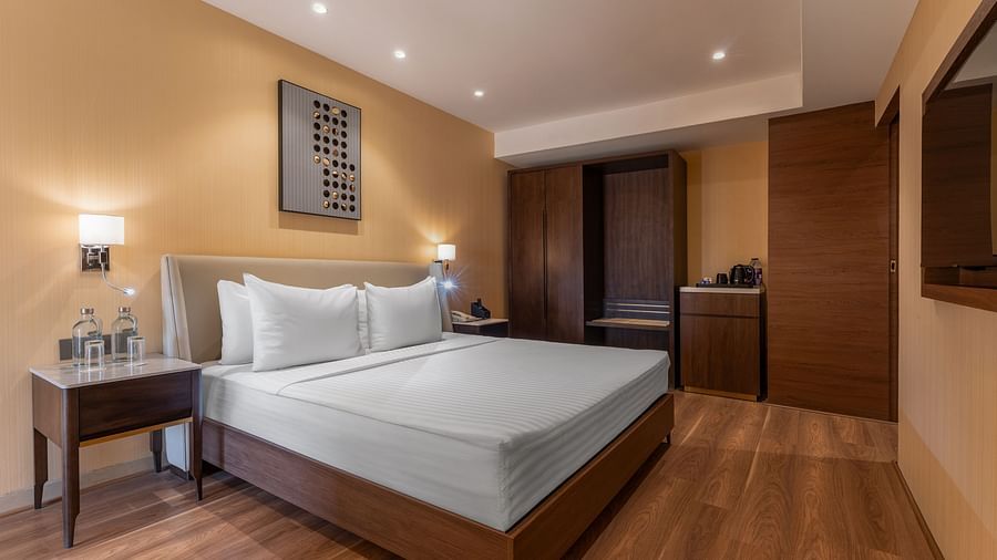  Modern bedroom with wood flooring, double bed, wardrobe, and soft yellow lighting at Clarks Inn Suites, Hyderabad