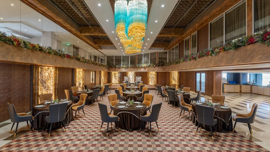 Grand dining area with round tables, stylish chairs and artistic ceiling decor at Clarks Inn Suites, Hyderabad