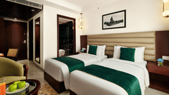 An image of the executive twin bed room with two large beds placed against a wall with a painting placed on it - Deventure Sarovar Portico, Patel Nagar