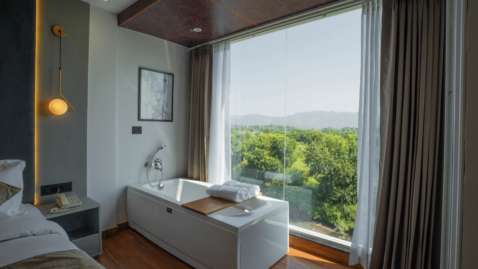 A guest room at Sukoon by the Ganges featuring a deep soaking tub right next to a window with lush green views.