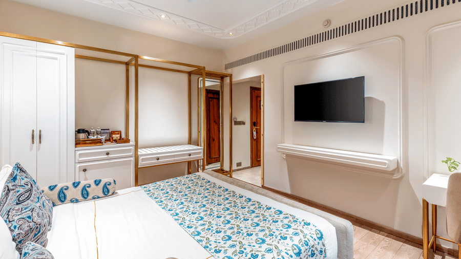 An overhead shot of the Premium room showcasing a neat double bed facing the wall-mounted television in a brightly lit room - Amantra Comfort Hotel